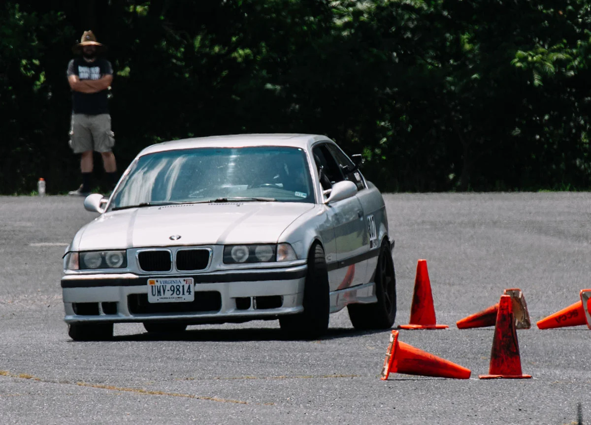 An E36 M3 pushing hard mid-corner on an autocross course.